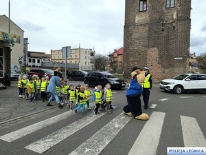 dzieci ubrane w kamizeli odblaskowe przechodzą przez ulicę
