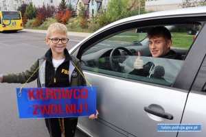 Chłopiec z plakatem &amp;quot;Kierowco zwolnij&amp;quot; pozuje z kierowcą do zdjęcia