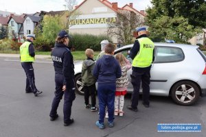 Dzieci i policjanci rozmawiają z kierowcą na temat bezpieczeństwa