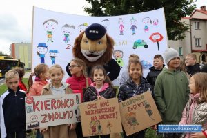 Grupa dzieci z transparentami i komisarzem lwem pozują do zdjęcia