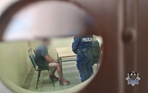 przesłuchanie podejrzanego przez policjanta - widok przez wizjer