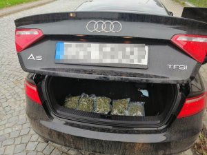 W otwartym bagażniku auta widać worki z marihuaną.