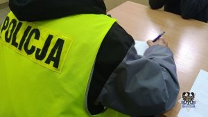 osoba w kamizelce z napisem policja, pisze.