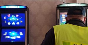 automaty do gier i stojący tyłem policjant