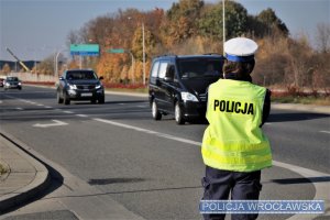 policjant stoi przy drodze i kontroluje ruch