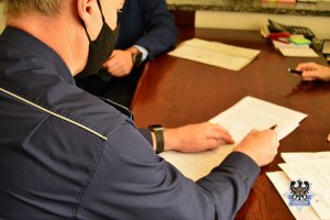Komendant Wojewódzki podpisuje akt notarialny przekazani działki pod budowę komisariatu. Na biurku leżą dokumenty