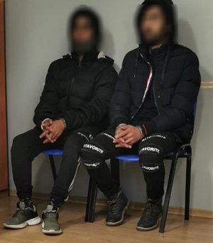 dwa zatrzymani siedzący na krześle