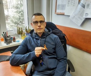 Policjant w cywilnym ubraniu trzyma pomarańczową wstążeczkę