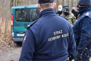 funkcjonariusz Straży Ochrony Kolei i Policjant stoją przy samochodzie straży granicznej