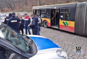policjanci kontrolują wysiadających z autobusu miejskiego pasażerów pod kątem noszenia maseczek