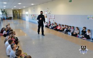 Policjant rozmawia z dziećmi na szkolnym korytarzu