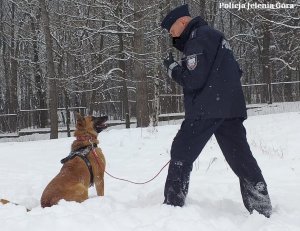 policjant z psem bawi się na śniegu
