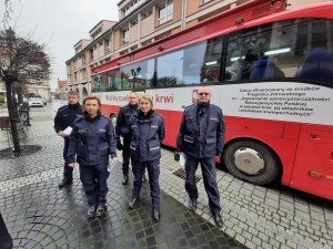 policjanci w mundurach stojący przed krwiobusem