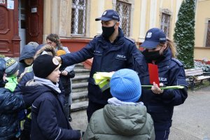 policjanci rozdają dzieciom kamizelki odblaskowe