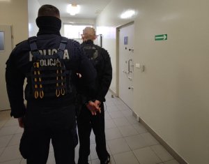 policjant prowadzi zatrzymanego mężczyznę do aresztu