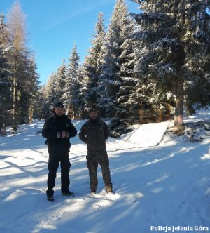 Policjant i strażnik leśny stoją na stoku góry pokrytej śniegiem.