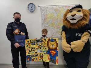 Na zdjęciu widać stojących od lewej: Komendanta Powiatowego Policji z Oławy, chłopca, który zwyciężył w konkursie plastycznym oraz Komisarza Lwa