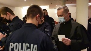 dzielenie się opłatkiem kapelana z policjantem