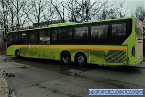 Autobus koloru jasnozielonego zaparkowany na jezdni asfaltowej.