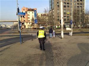 policjanci w rejonie przejścia dla pieszych kontrolują bezpieczeństwo