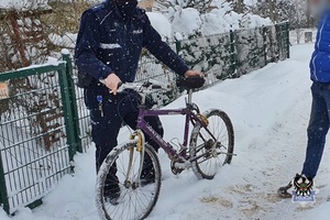 policjant trzyma na śniegu rower