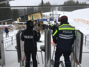 policjanci wjeżdżają na nartach na wyciąg