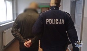 Policjant prowadzi zatrzymanego mężczyznę