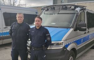 Policjanci stoją przy radiowozie