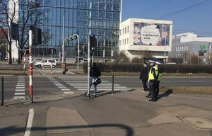 Policjanci stoją przy przejściu dla pieszych i obserwują zachowania uczestników ruchu drogowego