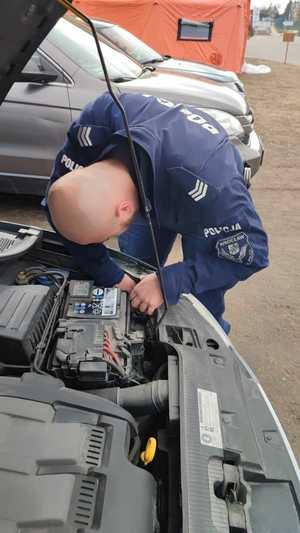 policjant pomaga przy naprawie auta