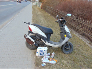 skuter stojący na poboczu, obok na trawniku leżą puszki z piwem