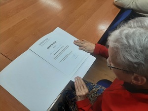 seniorka ogląda otrzymany certyfikat