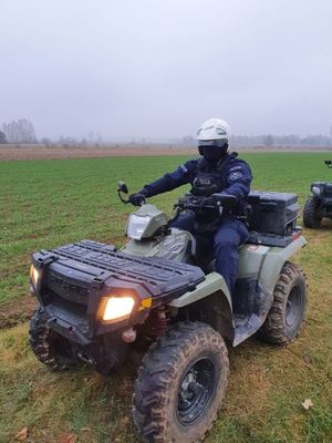 policjant stoi na drodze polnej siedząc na quadzie