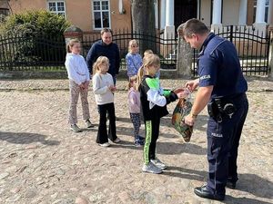 umundurowany policjant wręcza paczkę świąteczną dzieciom