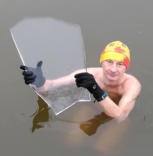 mężczyzna zanurzony w wodzie trzyma taflę lodu