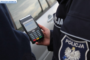 terminal trzymany przez policjanta i na nim wyświetlona kwota 5 tysięcy złotych