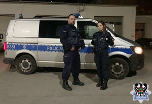 patrol policji stojący koło radiowozu, który udzielił pomocy osobie poszkodowanej