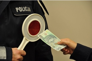 banknot wręczany jest policjantowi trzymającemu tarczę do zatrzymywania pojazdów