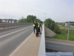 policjanci  stojący na wiadukcie mierzą prędkość przejeżdżających pojazdów