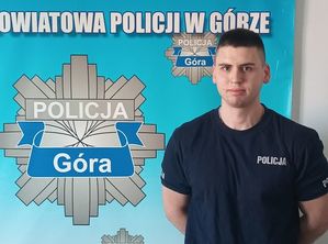 policjant stojący na tle planszy POLICJA GÓRA