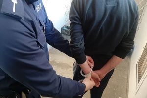 Policjant zakłada zatrzymanemu kajdanki