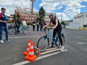 Uczennica jedzie na rowerze po przeszkodzie, obok stoi policjant