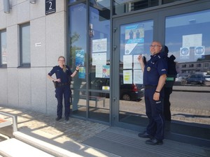 Policjanci stoją obok budynku.