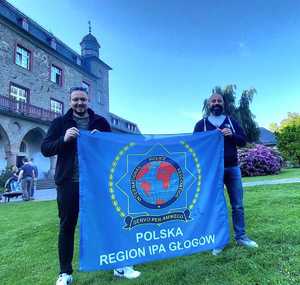 Dwóch policjantów trzyma flagę z logo IPA Region Głogów