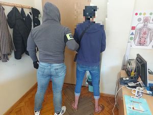 policjant stojący z zatrzymanym mężczyzną