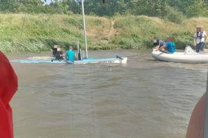 łódź zanurzona w wodzie i osoby próbujące ją wydostać