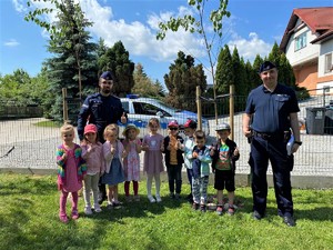 policjanci podczas wizyty w przedszkolu,z dziećmi na wspólnym zdjęciu widać radiowóz