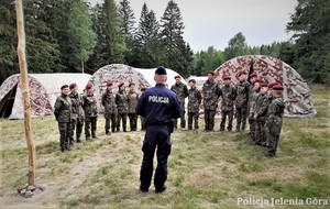 Zdjęcie przedstawia umundurowanego policjanta oraz grupę harcerzy