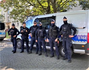 Zdjęcie przedstawia policjantów stojących przed radiowozem