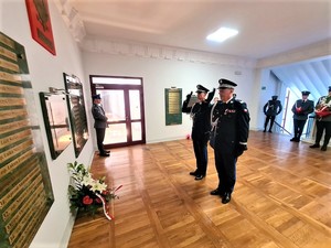 Komendant Wojewódzki Policji we Wrocławiu oddający honor przed tablicą upamiętniającą zmarłych policjantów